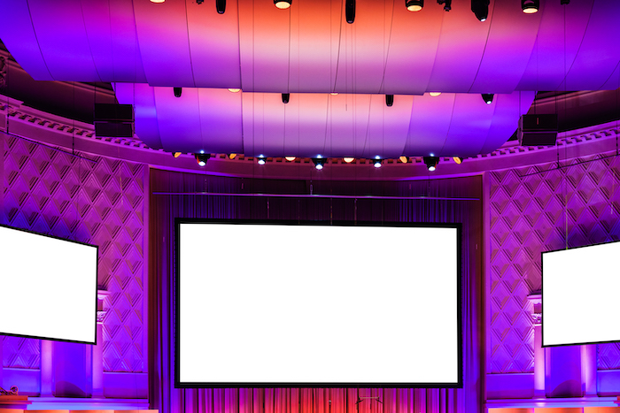 three empty cut out screens in pink, red and purple illuminated cinema theater